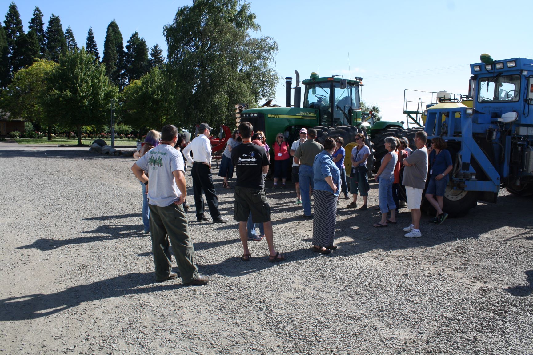 A gathering of SAI participants in front of a green and blue farm equipment